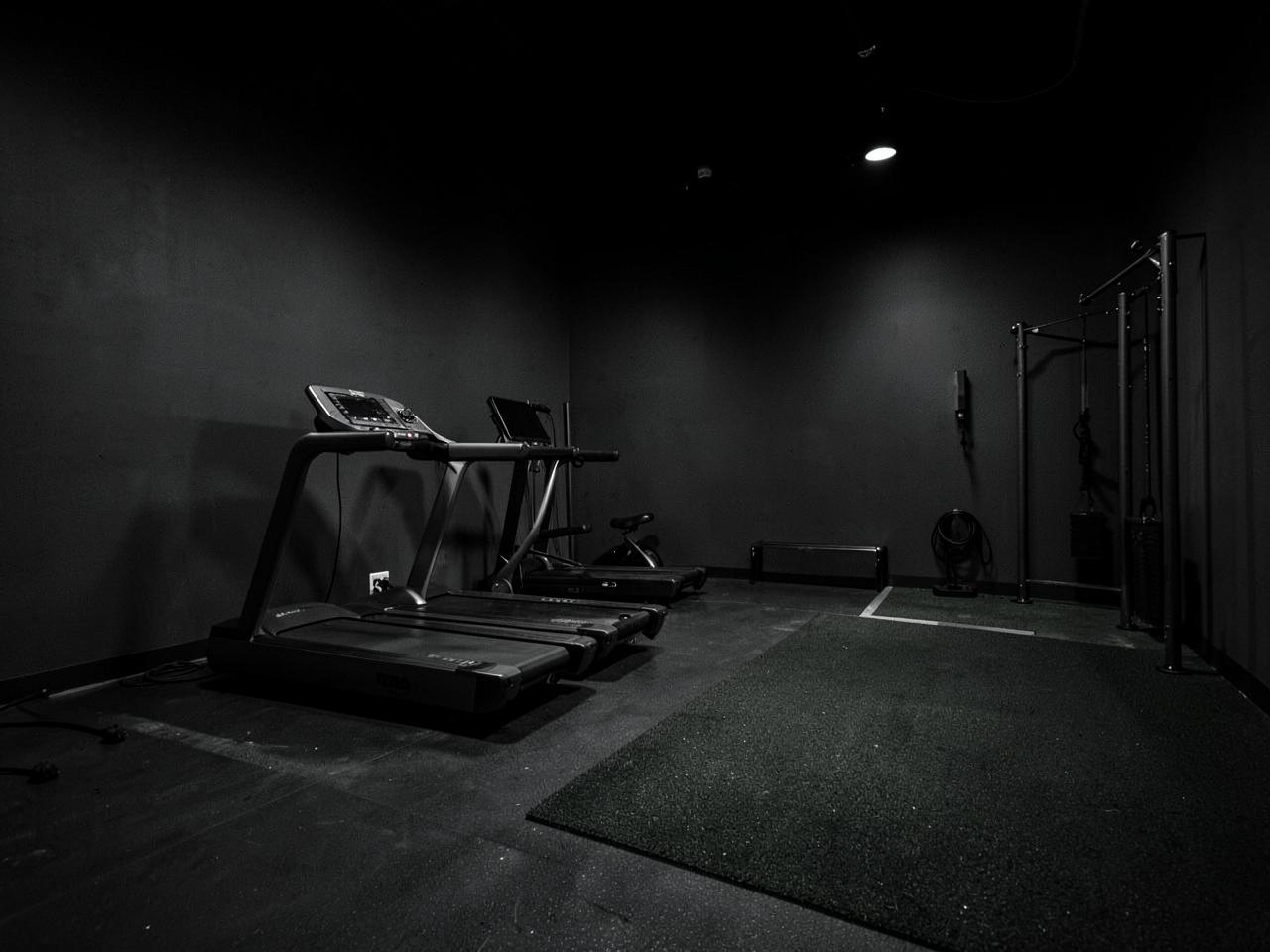 Treadmills and turf functional-training space in a dark gym